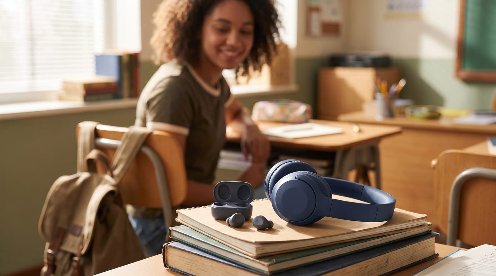 Affordable navy wireless headphones and earbuds on a student desk