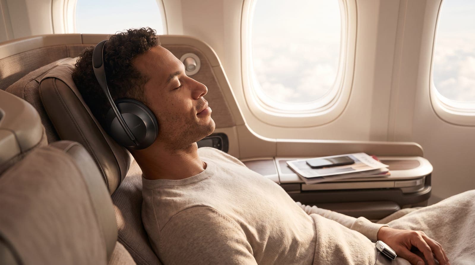 Man relaxing in an airplane seat wearing black over-ear noise cancelling headphones